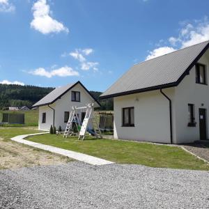 a white house with a ladder next to it at Domek pod Holicą 2 in Ustrzyki Dolne