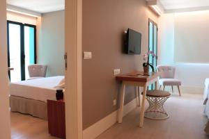 a bedroom with a bed and a desk and a tv at Hotel Almirante in Alicante