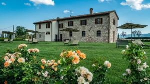 圣维塔勒Borgo Degli Angeli Resort e Spa的一座大型石头建筑,前面有雨伞和鲜花