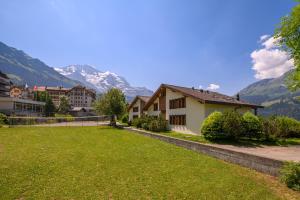 una casa con césped y montañas al fondo en Chalet Primula Penthouse, en Wengen