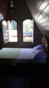 a bedroom with two windows and a bed in it at Chalet da vila in Angra dos Reis