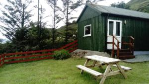 a green building with a picnic table in front of it at Harbor View in Uig