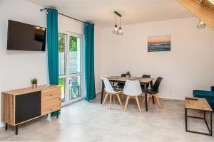 Un comedor con mesa y sillas y un televisor. en Wiatrem Pisane, en Władysławowo 9 fotos más
