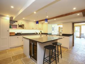 a large kitchen with a large island with two bar stools at Kings Cottage - South in Broad Chalke