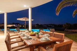 a wooden table with plates of food on a patio at Villa Rocamar in Cala en Blanes