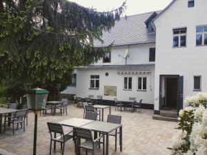 a patio with tables and chairs in front of a white building at Gasthof Uttewalde in Uttewalde