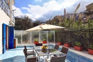 patio con tavolo e ombrellone di A Taste of Sun Apartment a Sorrento