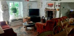 a living room with a tv and a couch and chairs at Cozy Carbence Cottage in Carbis Bay