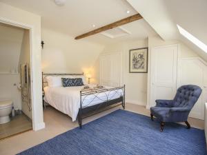 um quarto com uma cama e uma cadeira azul em Kings Cottage - North em Broad Chalke