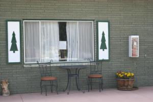 a table and chairs in front of a green brick wall at Bryce Zion Inn in Hatch