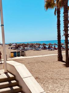 una playa de arena con palmeras y sombrillas en Hotel Costamar, en Morche