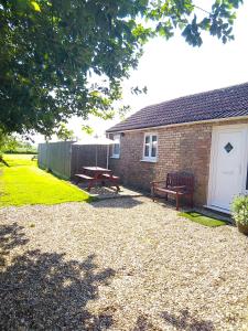 a brick building with a picnic table and a bench at Little Owls Nest Holiday Home in Wisbech