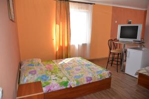 a bedroom with a bed and a desk with a television at Domik na Fontane in Odesa