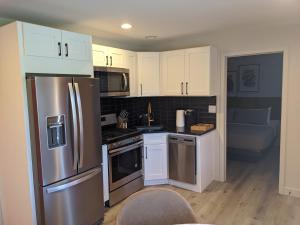a kitchen with white cabinets and a stainless steel refrigerator at 4411 Inn & Suites in Michigan City