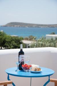 a blue table with a bottle of wine and glasses at Flora & Agelos Studios in Chrissi Akti