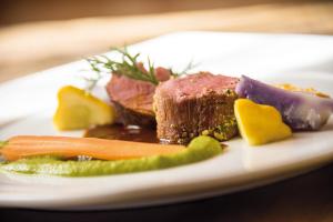 un plato de comida con carne y verduras en una mesa en Parkhotel Holzerhof en Maranza