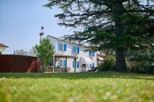 a white house with blue shutters and a tree at Cà del Mar rustico a Jesolo con giardino e piscina privati ad uso esclusivo # in Jesolo