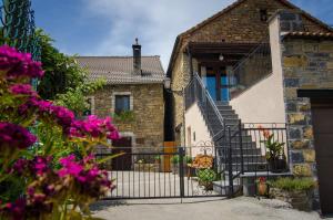 a house with a gate and purple flowers at Borda Diego in Ligüerre de Ara