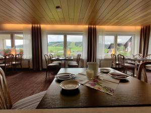 a dining room with a table and chairs and windows at Hotel Magdalenenhof inklusive MeineCardPlus in Willingen