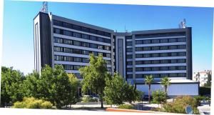 un grand bâtiment noir avec des arbres devant lui dans l'établissement Buyuk Saruhan Hotel, à Manisa