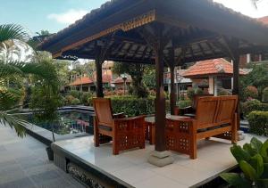 a wooden gazebo with two chairs and a table at Dewa Bharata Bungalows Legian in Legian