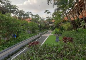 un jardín con árboles y plantas en un edificio en Dewa Bharata Bungalows Legian, en Legian