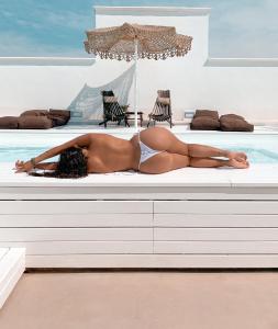 une femme qui pose sur un banc à côté d'une piscine dans l'établissement Playa del Mar - Adults Only, à Monopoli