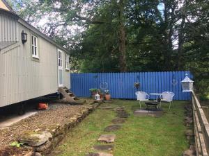a backyard with a blue fence and a table and chairs at Posh Huts Farmstay in Falstone