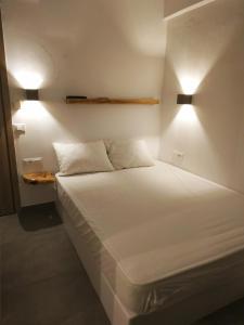 a bedroom with a white bed with two lights on it at ENALION-TINOS in Tinos Town