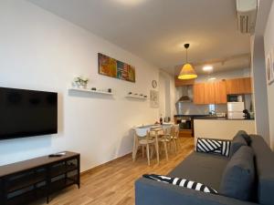 een woonkamer met een bank en een tv aan de muur bij Apartments Sant Lluis CENTER, 2 min walk from the sea in Lloret de Mar