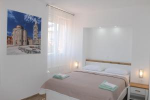 a white bedroom with a bed with a picture on the wall at Jeta Studio & Rooms in Zadar
