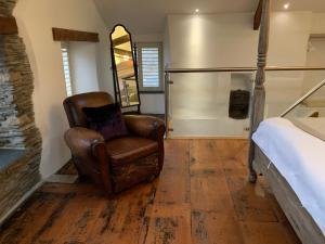 een slaapkamer met een leren stoel en een bed bij The Padstow Cottage (Coswarth House) in Padstow