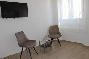 two chairs and a table with a tv on a wall at Jeta Studio & Rooms in Zadar