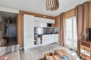 a living room with a kitchen with white cabinets at Cozy 1-bedroom with terrace - Bègles Welkeys in Bègles