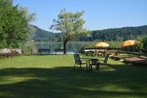 a group of tables and chairs next to a lake at Ferienwohnungen Wutte Josefine in Sankt Kanzian