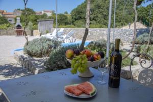 a table with a bottle of wine and a bowl of fruit at Traditional Stone House St.Anton in Malinska