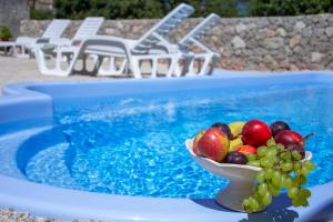 a bowl of fruit sitting on a table next to a swimming pool at Traditional Stone House St.Anton in Malinska