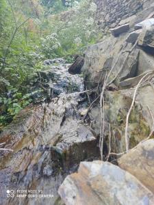 a stream on the side of a mountain with rocks at Casa da Neta in Açor