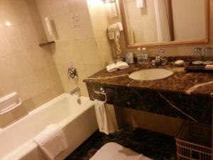 a bathroom with a sink and a bath tub at Qingdao Oceanwide Elite Hotel in Qingdao