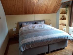 een slaapkamer met een groot bed en een houten plafond bij Den Donkman in Dessel
