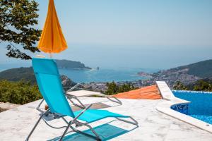 a blue chair and an orange umbrella sitting next to a swimming pool at Villas Adriatic Horizonte in Budva