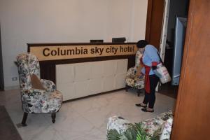 Una donna in piedi in un atrio con due sedie di columbia sky city hotel a Il Cairo