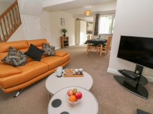 a living room with an orange couch and a flat screen tv at Nappers Cottage in Hayle