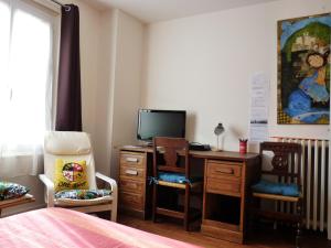 Schlafzimmer mit einem Bett und einem Schreibtisch mit einem TV in der Unterkunft La Maison des Lys in Chissey-lès-Mâcon