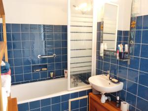 ein blau gefliestes Bad mit einem Waschbecken und einem Spiegel in der Unterkunft La Maison des Lys in Chissey-lès-Mâcon