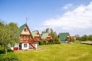 una casa de madera con techo verde en The Rainbow - Domki Letniskowe, en Dźwirzyno
