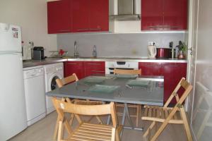 eine Küche mit roten Schränken sowie einem Tisch und Stühlen in der Unterkunft Charmante maisonnette aux portes de paris in Saint-Ouen
