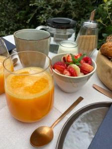 un tavolo con un bicchiere di succo d'arancia e un cesto di frutta di La Maison Moutchic a Lacanau