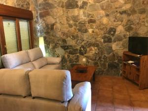 una sala de estar con 2 sofás y una pared de piedra. en El Relax de Sanabria, en Trefacio