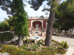 een groot rood huis met een fontein en bomen bij Villa Grazia in Latiano